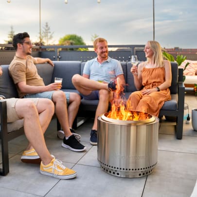 People sitting around a Solo Stove fire pit on a patio
